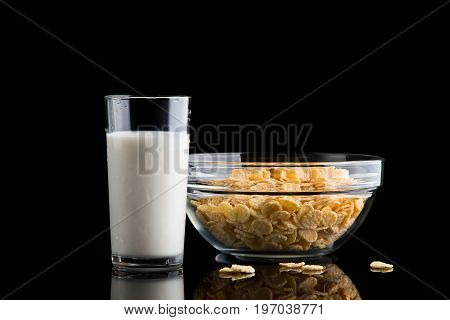 Glass of milk and cornflakes on a black background. Crispy corn flakes for breakfast.