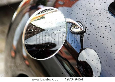 raindrops on a car reflections in the exterior mirror and in the shiny coating closeup