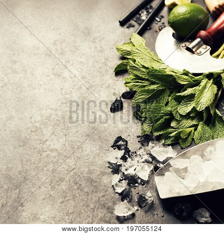 Mojito cocktail ingredients (fresh mint, lime, ice) on rustick background