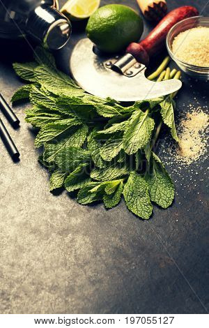 Mojito cocktail ingredients (fresh mint, lime, ice) on rustick background