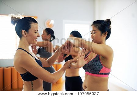 Multi-ethnic group of talented women rehearsing contemporary dance while their middle-aged coach helping them with position of arms