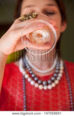 Beautiful woman in the red blouse drinking champagne. Close-up.