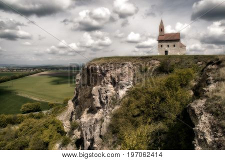 Romantic Drazovsky church on the hill Slovakia. Cloudscaoe over dark country