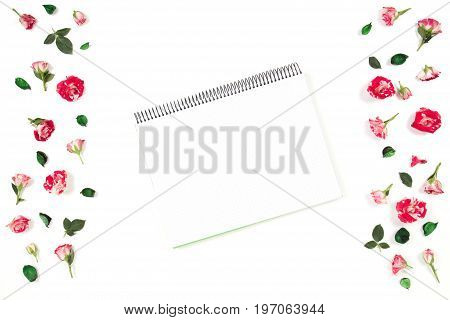 Open spiral notebook and rose flowers frame. Flat lay, top view