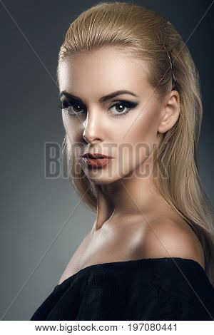 Portrait of a beautiful female model on dark background in a black dress