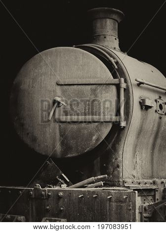 old rusty steam locomotive with door and chimney front view on black background