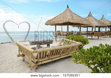 A place for two at a beautiful send beach of Gili Travangan island with ocean on a background and two chairs under umbrella, Indonesia