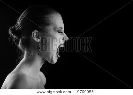 angry nude girl screaming on black background, monochrome