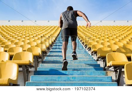 Back view of a young man running upstairs at a stadium