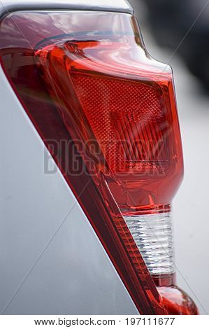 Left rear tail light from a car parked in at an office building on a sunny day just prior to lunch.