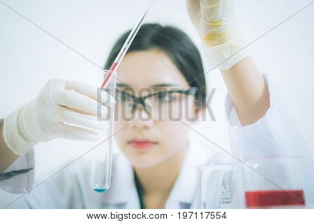 Young Asian scientist working in the lavatory with test tubes and other equipment to discover new drugs products and methods of formulation