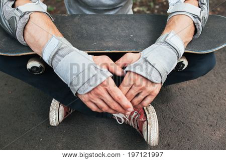 Skateboard halmet, elbow and gloves protection on unrecognizable skateboarder. Head and hands care. Extreme sport injoury. Headwear stuff for skater