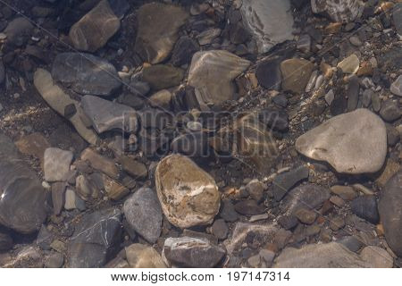 Stones in the mountain river. Ripples on the water in the mountain stream. Selective field of focus.