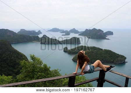 woman sitting on top of a mountain and looking the view at angthong island