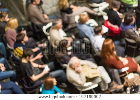 Abowe shot of blured audience in conference hall. Presentation in lecture hall at university workshop. Rear view of unrecognized participant in audience. Scientific conference event.