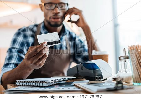 African American Male Owner Working With Credit Card Reader And Smartphone In Coffee Shop