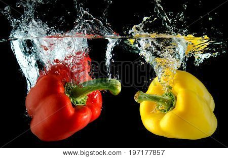 Splash water from water droping bell pepper in black background with studio lighting.