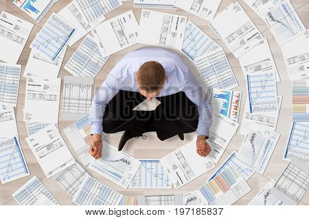 Elevated View Of A Businessman Doing Meditation Surrounded With Various Business Documents
