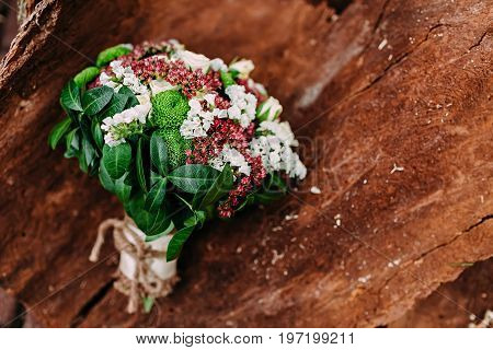 Rustic wedding bouquet with different flowers and greens on wooden background. Top view.