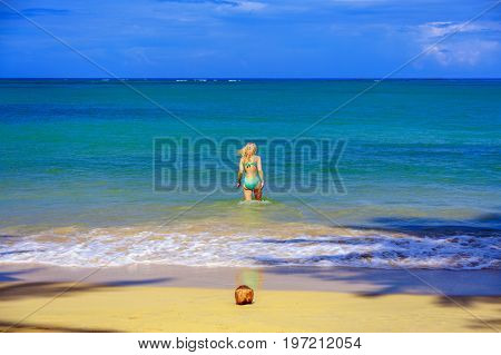 Girl going to the sea. Coconut on the beach