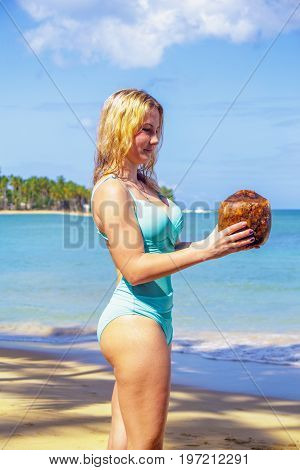 Young girl holding coconut on the beach