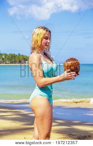 Young girl holding coconut on the beach