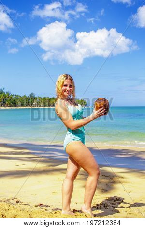 Young girl holding coconut on the beach