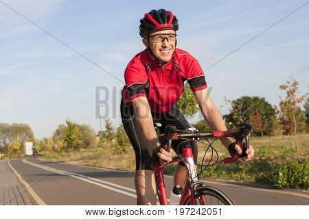Cycling Concepts and Ideas. Smiling Caucasian Road Cyclist During Ride on Bike Outdoors. Completely Equipped in Professional Outfit.Horizontal Shot