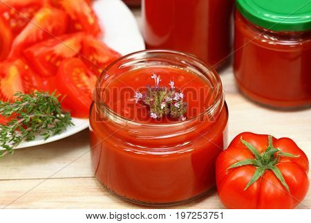 Making homemade preserved ketchup with oregano spice jars of fresh ketchup at the background