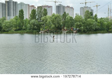 Man is engaged in wakeboarding on the background of construction