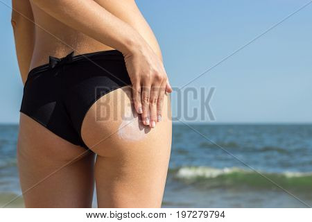 Suntan Lotion Woman Applying Sunscreen Solar Cream. Beautiful cute girl applying Sun Tan Cream on her skin on the beach. Sun Tanning. Skin care and Protection. Vacation