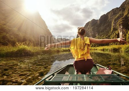 Joyful tourist travels along the river Ngo Dong with beautiful algae Cabomba Ninh Binh province Vietnam. Scenic sunset on a background of karst mountains
