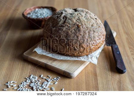 Freshly Baked Homemade Bread On Wooden Board With Knife And Sunflower Seeds On The Table, Selective