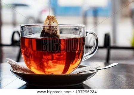 Closeup teabag put in water in teacup on saucer