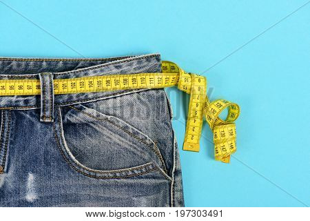 Upper Part Of Jeans With Measure Tape On Blue Background