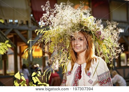Portrait of a romantic smiling woman in a circlet of flowers outdoors.