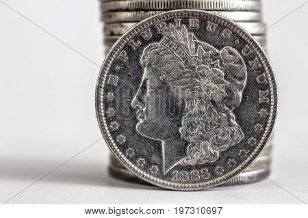 1883 Morgan Dollar coin stands against a stack of coins.