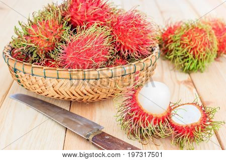 fresh tropical rambutan fruits over basket with knife on wooden table background fruit in Thailand
