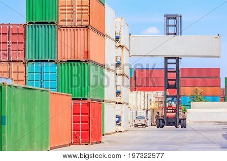 Forklift truck lifting cargo container in shipping yard or dock yard against blue sky cloudy with cargo container stack in background for transportation import Export and logistic industrial concept