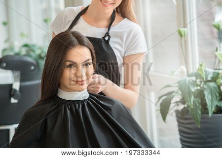 Young female sitting in hair salon hairdo styling button up pelerine