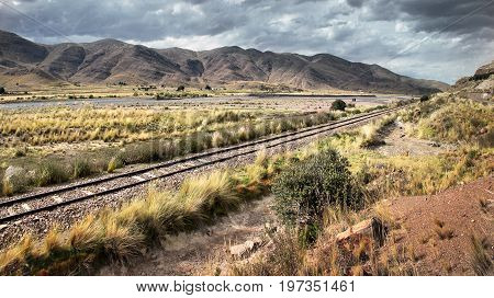 A railway track leading through the dry landscape of southern Peru
