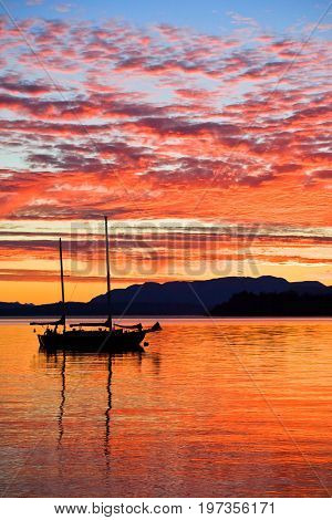 Silhouetted sailboat at sunset on the west coast of British Columbia, Canada