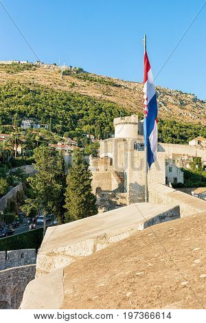 Old City Walls With Flag And Fort Minceta In Dubrovnik