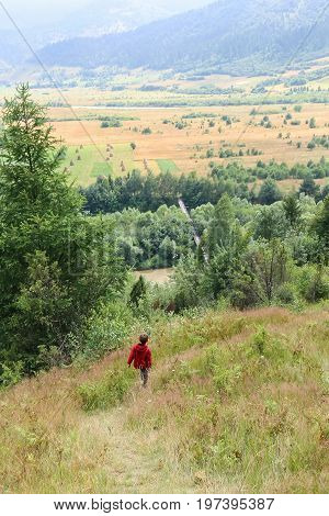 Boy walks picturesque hills of Carpathians. Schodnica Ukraine