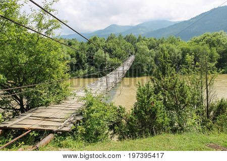 Suspended wooden bridge across Schodnica river in Carpathians Ukraine