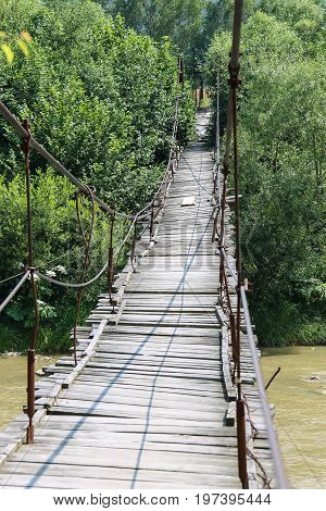 Suspended wooden bridge across Schodnica river in Carpathians Ukraine