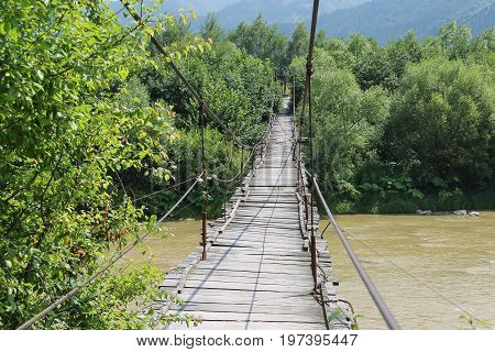Suspended wooden bridge across Schodnica river in Carpathians Ukraine