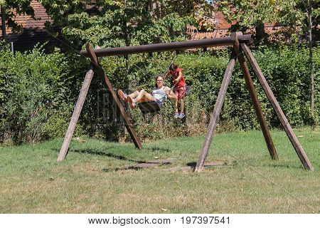 Grazzano Visconti Italy - August 07 2016: Children ride on wooden swing