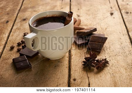 Cup of hot chocolate drink cinnamon sticks boken dark chocolate bar and coffee beans on old wooden rustic table