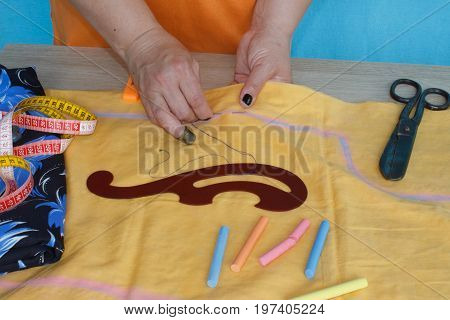 Woman's hand sewing fabric with sewing equipments. female in costume sewing